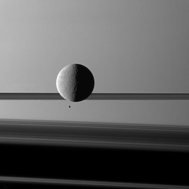 Saturn moon Rhea looms over a smaller and more distant Epimetheus against a striking background of planet and rings. The two moons arent actually close to each other.