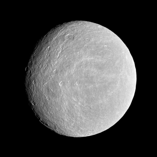 NASA Cassini spacecraft looks toward the cratered plains of the trailing hemisphere of Rhea. Some of the moon fractures, appearing like wispy bright lines, can be seen on the left of the image.