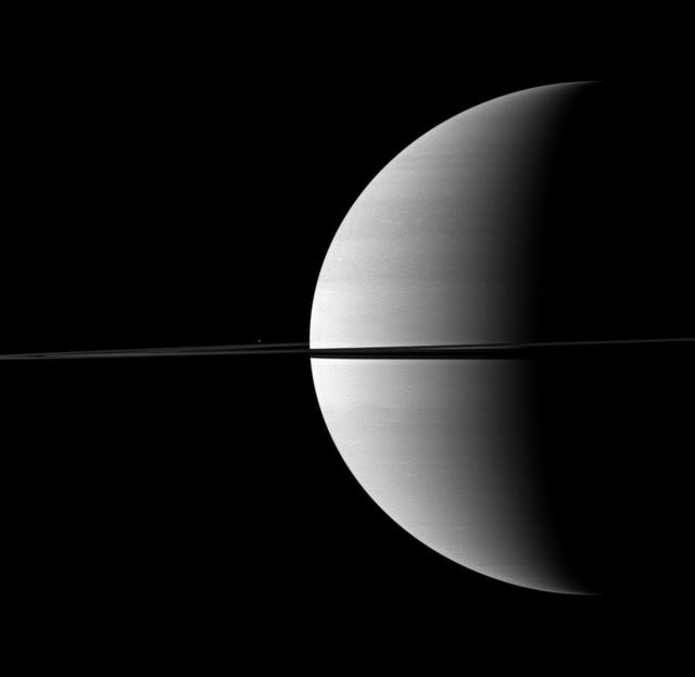 Nearly invisible upon first glance, Saturn moon Enceladus is a small bright dot beyond the planet rings in this image taken by NASA Cassini spacecraft.