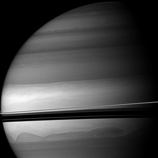 Huge clouds swirl through the southern latitudes of Saturn where the rings cast dramatic shadows. This view from NASA Cassini spacecraft looks toward the northern, sunlit side of the rings from just above the ringplane.