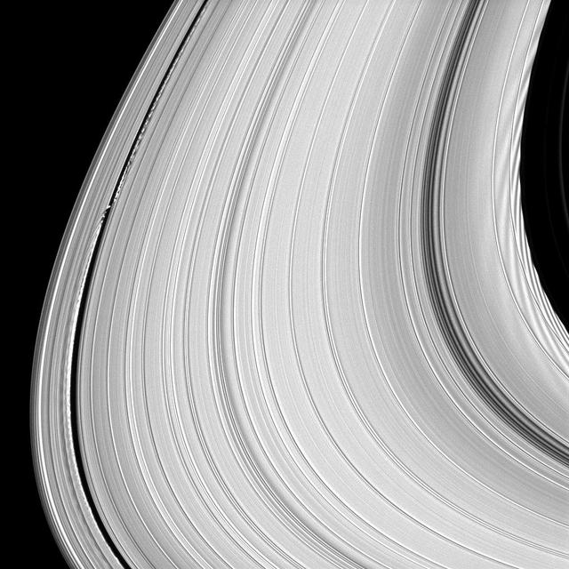 This image taken by NASA Cassini spacecraft shows that rather than being an unchanging disk of peaceful particles, the material that makes up Saturn rings is constantly pushed and pulled into spectacular shapes. At left is the moon Daphnis.