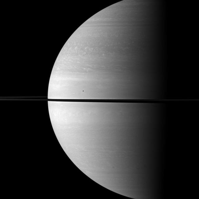 The immense size of Saturn is emphasized in this portrait by NASA Cassini spacecraft that features the moon Mimas shown in front of the planet. Mimas appears as only a small dot above the rings near the center of the image.