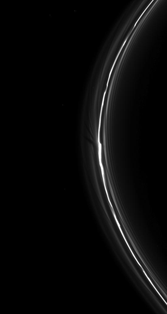 NASA Cassini spacecraft spies a fan in Saturn tenuous F ring. This fan-like structure appears as dark lines spreading outward from the left of the bright clump of ring material near the center of the image.