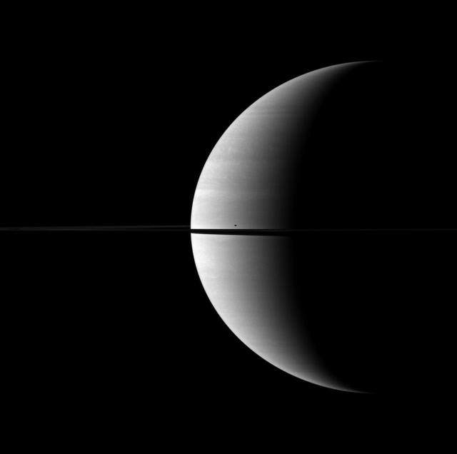The moon Mimas casts a shadow and creates a single blemish on the kingly crescent of Saturn. Mimas is not shown in this view, but its shadow can be seen on the planet just north of the rings and their shadow.