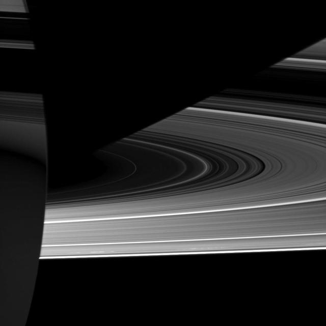 Capturing the interplay between light and shadow, NASA Cassini spacecraft looks toward the night side of Saturn where sunlight reflected off the rings has dimly illuminated what would otherwise be the dark side of the planet.