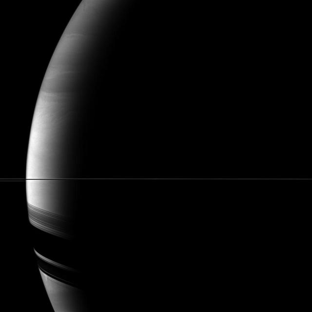 Saturn rings appear as only a thin line seen edge-on in the middle of this view from NASA Cassini spacecraft, but the rings cast broad shadows on the southern hemisphere of the planet in the lower left of the image.