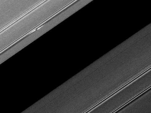 A propeller-shaped structure created by an unseen moon is brightly illuminated on the sunlit side of Saturn rings in this image obtained by NASA Cassini spacecraft. The moon, which is too small to be seen, is marked with a red arrow.