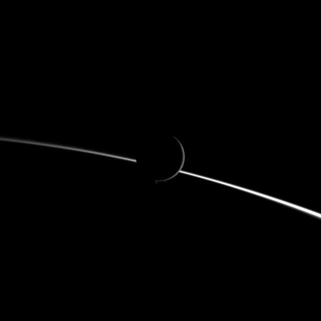 Jets of water ice particles spew from Saturn moon Enceladus in this image obtained by NASA Cassini spacecraft on Aug. 13, 2010. A crescent of the moon appears dimly illuminated in front of the bright limb of Saturn.