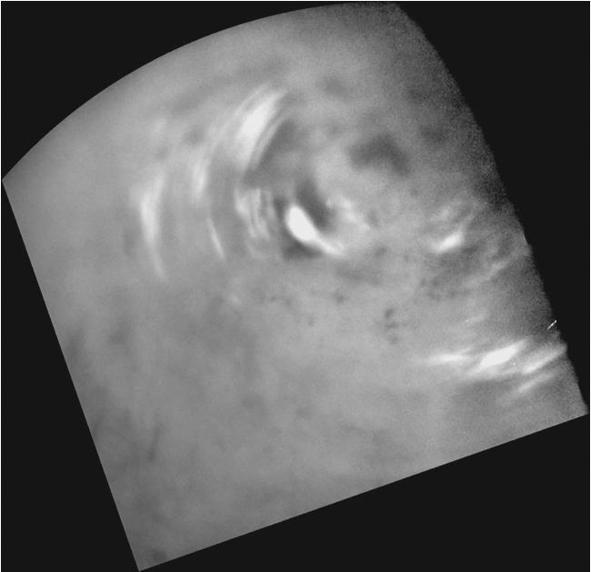 Clouds move above Titan large methane lakes and seas near the moon north pole in this image from NASA Cassini spacecraft. Methane clouds in the troposphere, the lowest part of the atmosphere, appear white here.