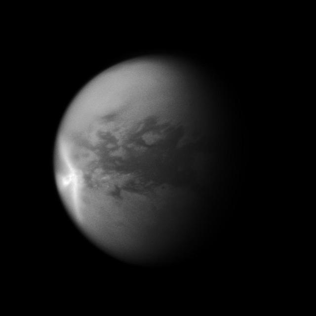A huge arrow-shaped storm blows across the equatorial region of Titan in this image from NASA Cassini spacecraft, chronicling the seasonal weather changes on Saturn largest moon.