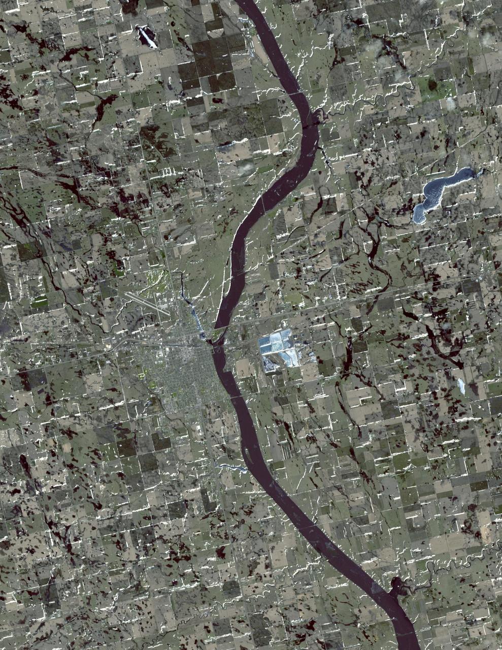 In this simulated natural color image of Huron, South Dakota, captured by NASA Terra spacecraft on March 20, 2010, frozen lakes and ponds appear blue, bare fields are tan, and fields with minor vegetation are gray-green.