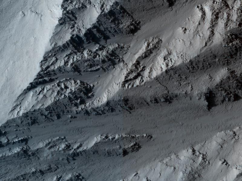 This image taken by NASA Mars Reconnaissance Orbiter covers the northern edge of the largest volcano in the solar system, Olympus Mons on Mars; its margin is defined by a massive cliff many kilometers several miles tall.