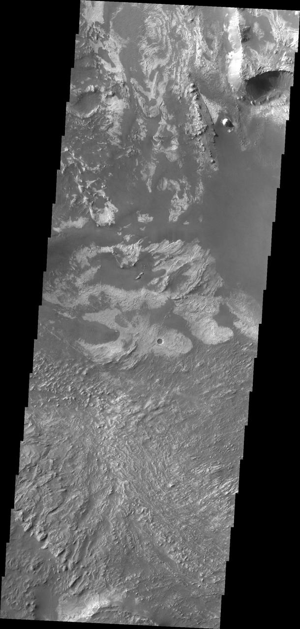 This image taken by NASA 2001 Mars Odyssey shows a portion of the floor of Melsa Chasma. Wind blown material is located in lows between layered floor materials.