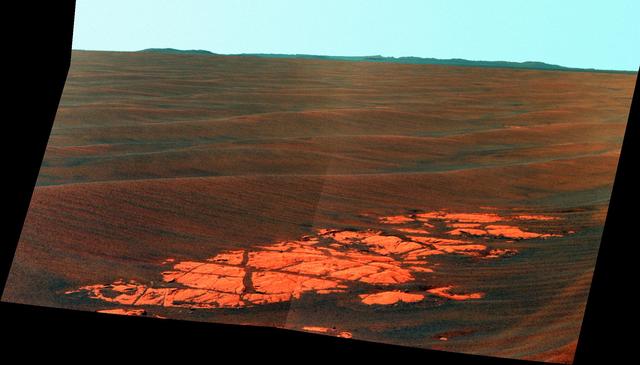 NASA Mars Exploration Rover Opportunity used its panoramic camera Pancam to capture this false-color view of the rim of Endeavour crater, the rover destination in a multi-year traverse along the sandy Martian landscape.
