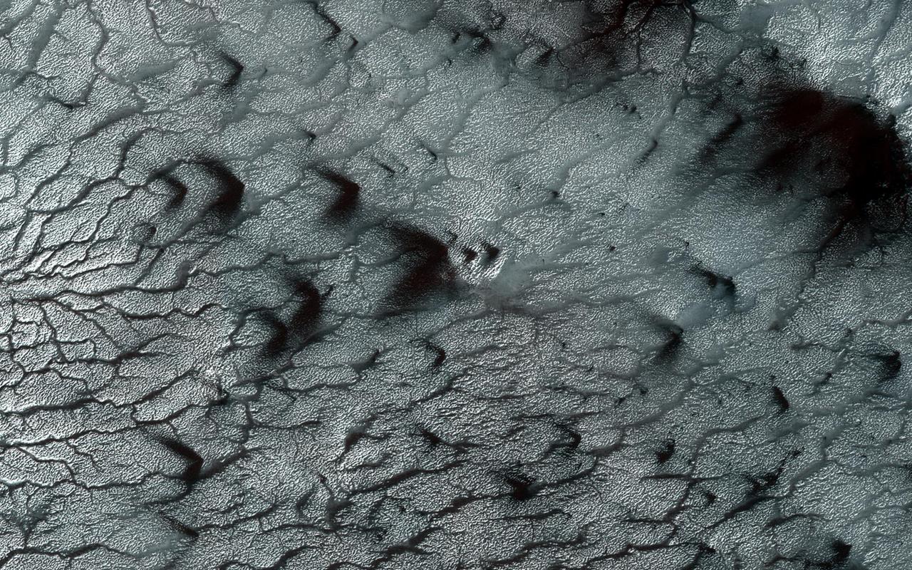 Southern spring on Mars brings sublimation of the seasonal dry ice polar cap. Gas trapped under the seasonal ice sheet carves channels on its way to escaping to the atmosphere.  At this site, the channels are wider than we see elsewhere on Mars, perhaps meaning that the spider-like (or more scientifically, "araneiform") terrain here is older, or that the surface is more easily eroded. Seasonal fans of eroded surface material, pointed in two different directions, are deposited on the remaining ice.  http://photojournal.jpl.nasa.gov/catalog/PIA13151
