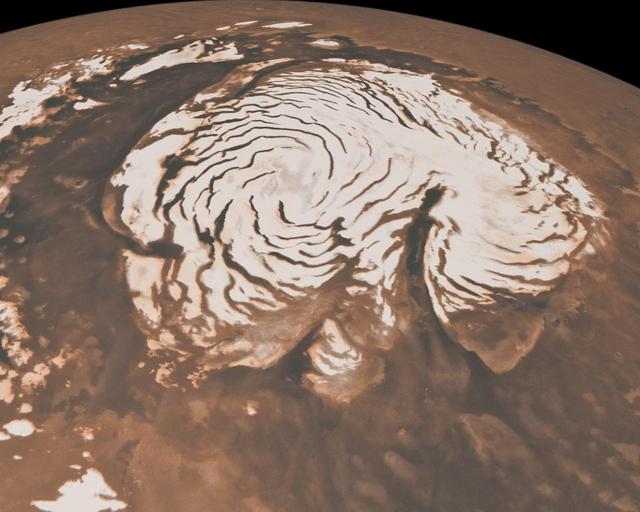 This image, combining data from two instruments aboard NASA Mars Global Surveyor, depicts an orbital view of the north polar region of Mars. To the right of center, a large canyon, Chasma Boreale, almost bisects the white ice cap.