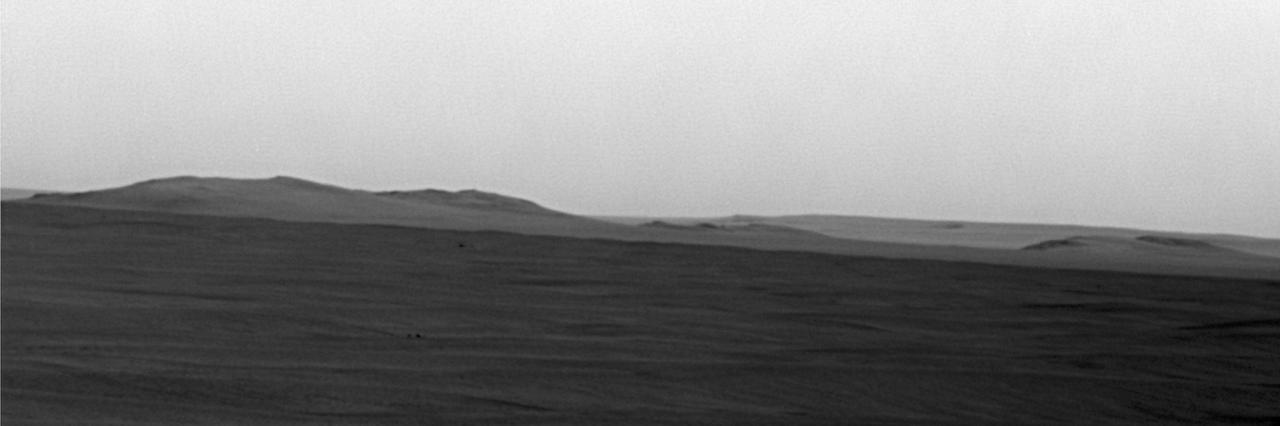 This image from NASA rover Opportunity shows mostly a portion of Endeavour western rim left; a paler-looking terrain on the horizon beyond Endeavour right is part of a thick deposit of material ejected by the impact that excavated Iazu Crater.