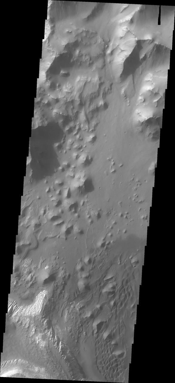 This image from NASA Mars Odyssey shows part of the floor of Ganges Chasma. Deposits of fine surface materials and bright layered deposits are visible in this image.