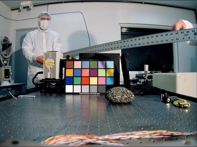 Ken Edgett, deputy principal investigator for NASA Mars Descent Imager, holds a ruler used as a depth-of-field test target. The instrument took this image inside the Malin Space Science Systems clean room in San Diego, CA, during calibration testing.