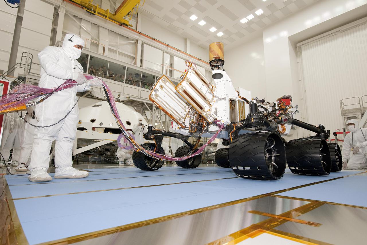 A test operator in clean-room garb holds umbilical cables for NASA Mars rover Curiosity during the rover first drive test, on July 23, 2010. NASA will launch Curiosity in late 2011 for arrival at Mars in August 2012.