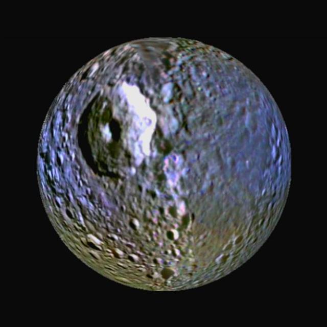 This enhanced-color view of Saturn moon Mimas was made from images obtained by NASA Cassini spacecraft. It highlights the bluish band around the icy moon equator. The large round gouge on the surface is Herschel Crater.