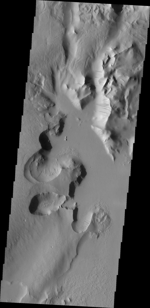Lycus Sulci is an extremely complex region surrounding the western and northern flanks of Olympus Mons. With a multitude of fault formed cliff faces, dark slope streaks are a common occurrence. This image was captured by NASA Mars Odyssey.