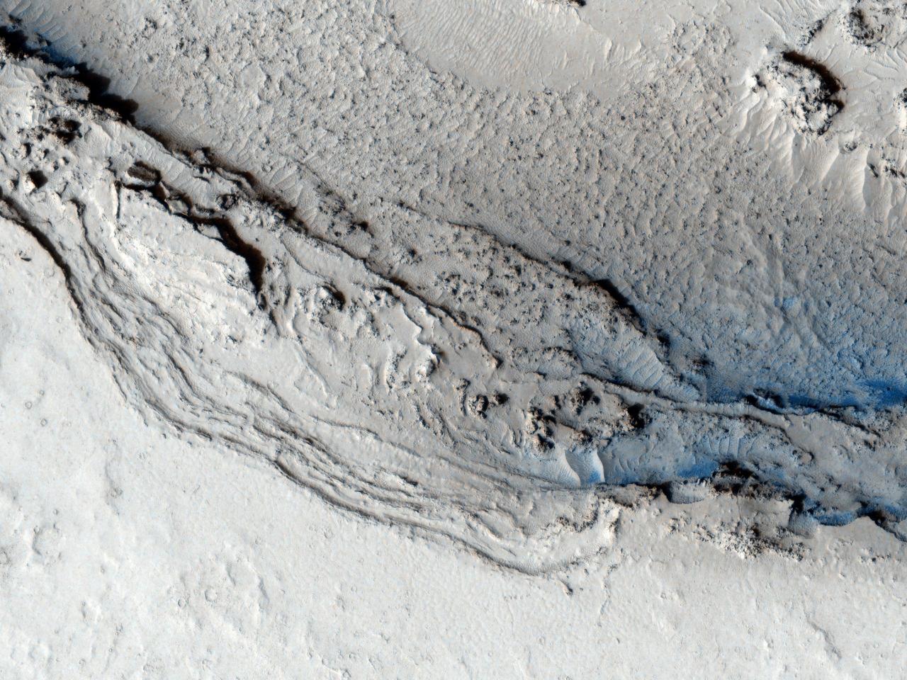 This image from NASA Mars Reconnaissance Orbiter shows the funnel-shaped terminus of Lethe Vallis, a winding channel in the Elysium Planitia region of Mars; the floor is covered in solidified lava and blanketed by a thin layer of light-toned dust.