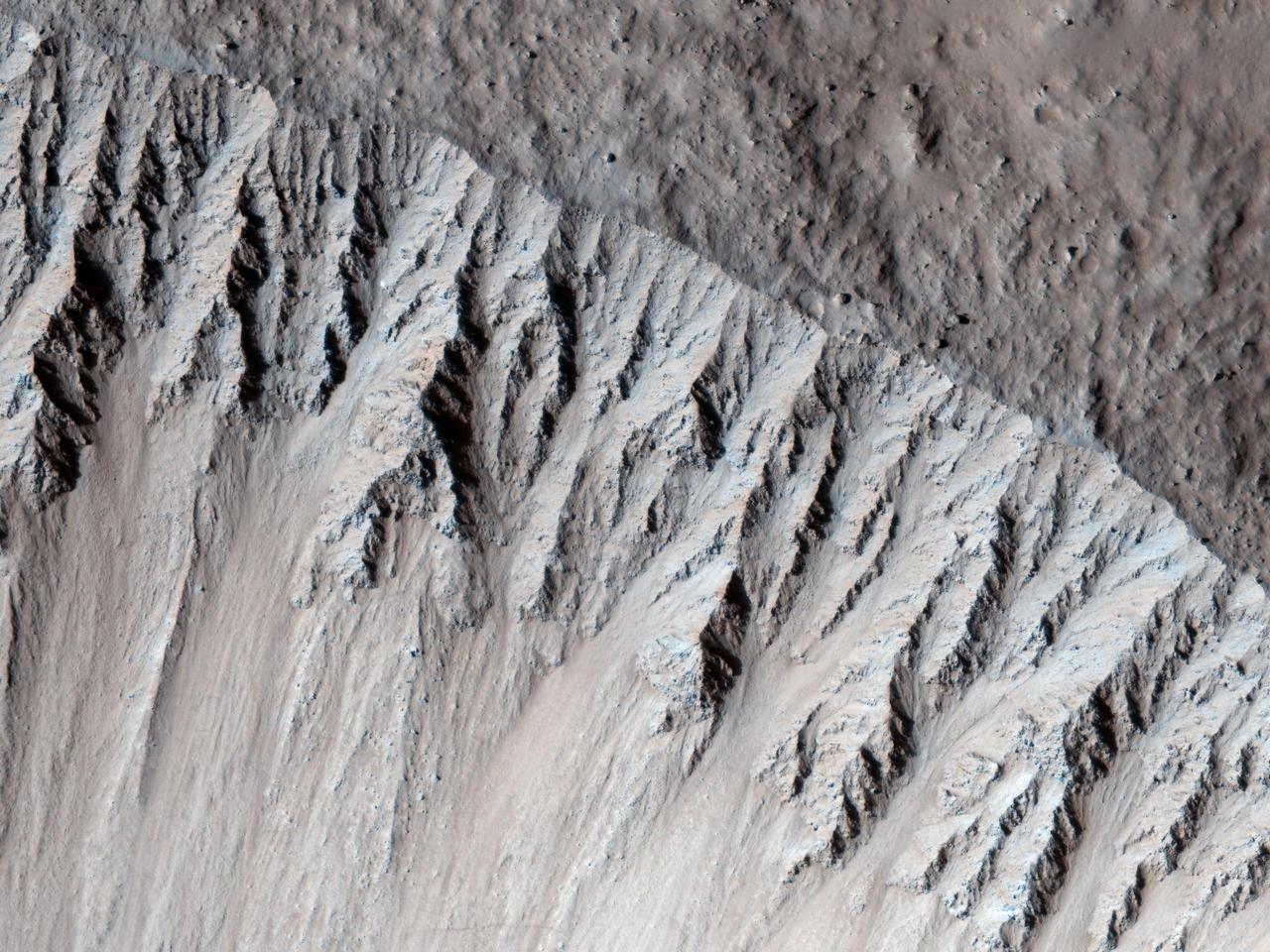 This image from NASA Mars Reconnaissance Orbiter is one of the rare examples of a fresh lunar-like crater on Mars. The impact crater formed in the Tharsis region.