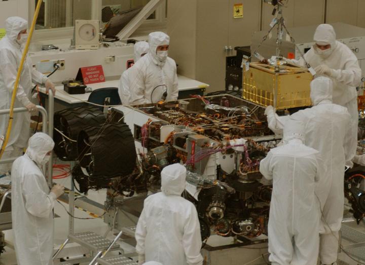 In this photograph, technicians and engineers inside a clean room at NASA Jet Propulsion Laboratory, Pasadena, Calif., position NASA Sample Analysis at Mars SAM above the mission Mars rover, Curiosity, for installing the instrument.
