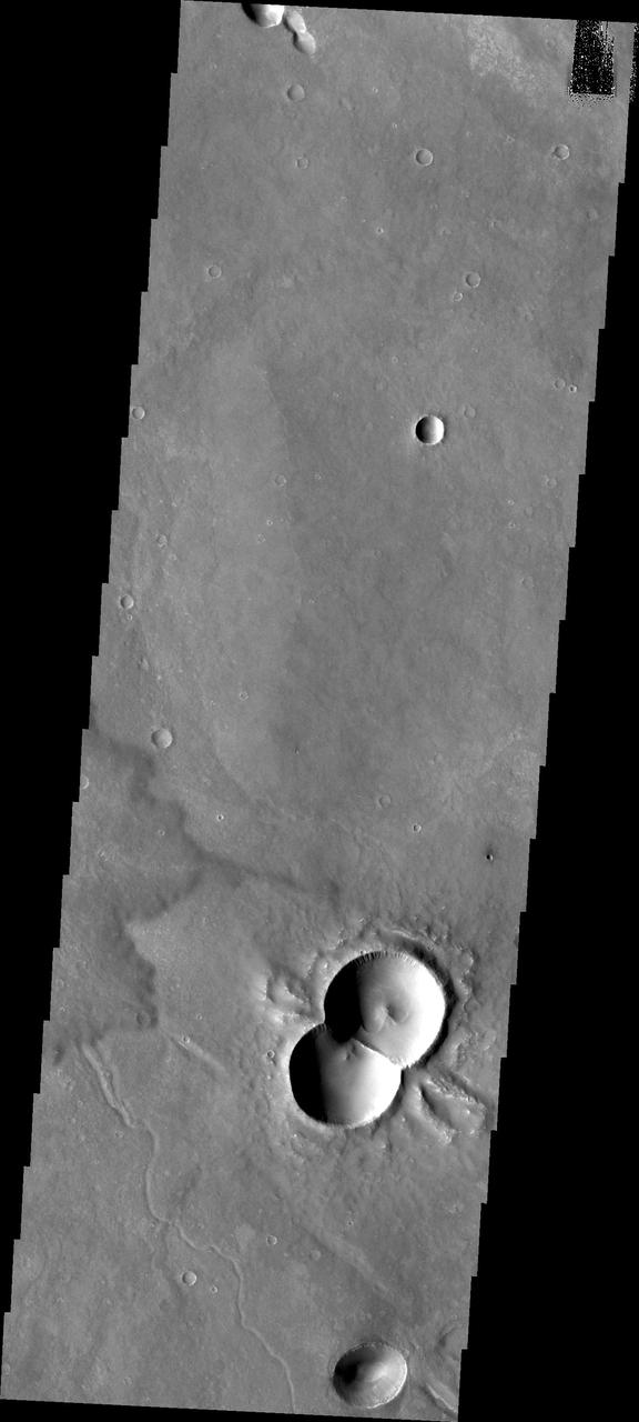 This doublet crater was formed when two meteorites impacted at the same time. The shock waves interact to form the straight central rim and the wings of ejecta on the outside of the rims. This image is from NASA Mars Odyssey.