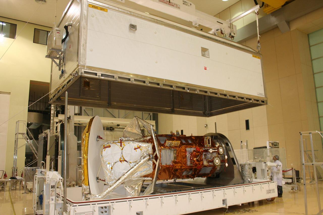 Technicians lower the cover over the shipping container holding the international Aquarius/SAC-D spacecraft at Brazil National Institute for Space Research.