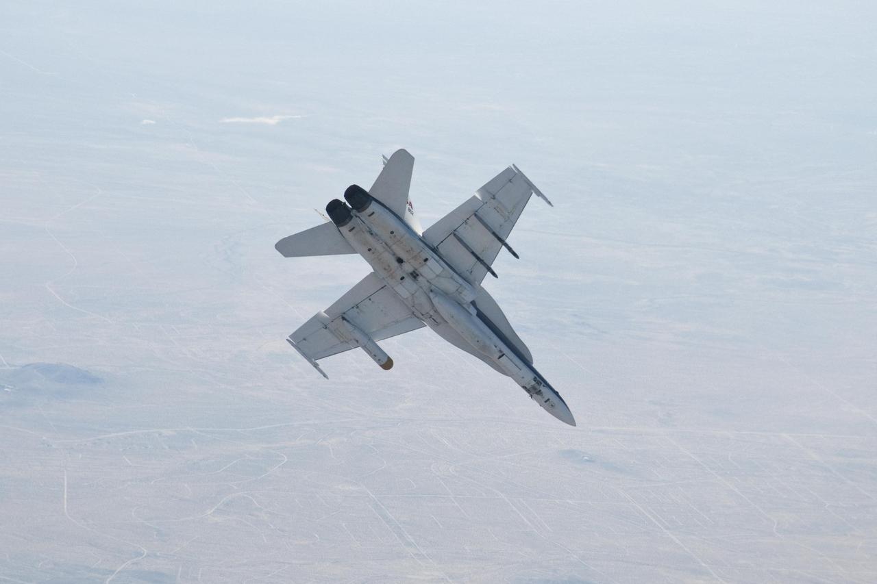 A NASA Dryden Flight Research Center F/A-18 852 aircraft performs a roll during June 2011 flight tests of a Mars landing radar. A test model of the landing radar for NASA Mars Science Laboratory mission is inside a pod under the aircraft left wing.