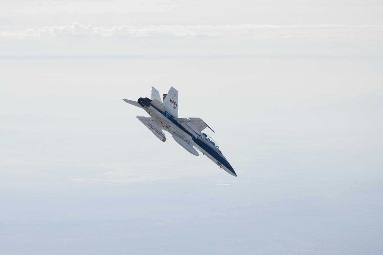 A NASA Dryden Flight Research Center F/A-18 852 aircraft makes a 40-degree dive during June 2011 flight tests of a Mars landing radar. A test model of the landing radar for NASA Mars Science Laboratory mission is inside a pod under the left wing.