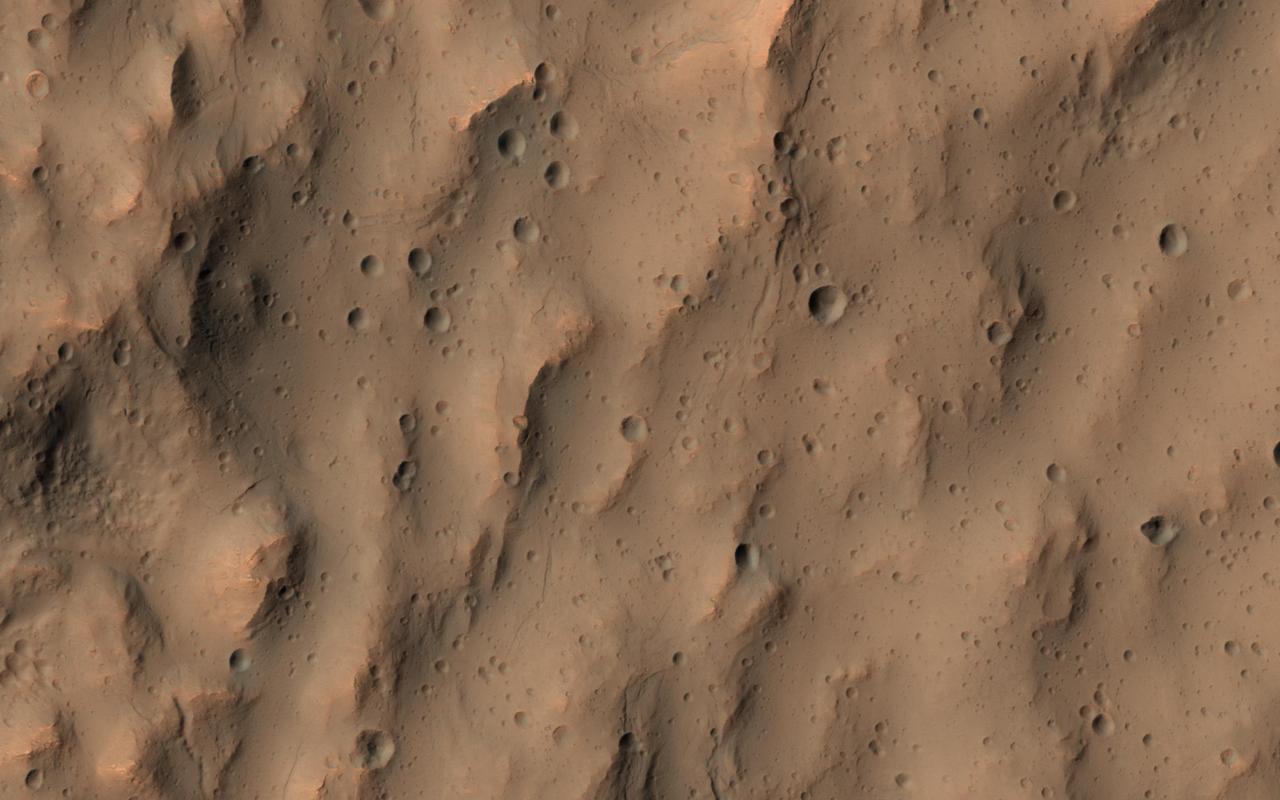 This image of a southern mid-latitude crater was intended to investigate the lineated material on the crater floor. At the higher resolution of HiRISE, the image reveals a landscape peppered by small impact craters. These craters range from about 30 meters in diameter down to the resolution limit (about 2 meter diameter in this image acquired by averaging 2x2 picture elements). Such dense clusters of small craters are frequently formed by secondary craters, caused by the impact of material that was excavated and ejected from the surface of Mars during the creation of a larger nearby crater by the impact of a comet or an asteroid. Secondary impact craters are both interesting and vexing. They are interesting because they show the trajectories of the material that was ejected from the primary impact with the greatest speeds, typically material from near the surface of the blast zone. Secondary craters are often found along the traces of crater rays, linear features that extend radially from fresh impact craters and can reach many crater diameters in length. Secondary craters can be useful when crater rays are visible and the small craters can be associated with a particular primary impact crater. They can be used to constrain the age of the surface where they fell, since the surface must be older than the impact event. The age of the crater can be approximately estimated from the probability of an impact that produced a crater of such a size within a given area of Mars over a given time period. But these secondary craters can also be perplexing when no crater rays are preserved and a source crater is not easily identifiable, as is the case here. The impact that formed these secondary craters took place long enough ago that their association with a particular crater has been erased. They do not appear along the trace of a crater ray that is still apparent in visible or thermal infrared observations. These secondary craters complicate the task of estimating the age of the lineated material on the crater floor. It is necessary to distinguish secondary craters from the primary impacts that we rely upon to estimate the ages of Martian surfaces. The large number of small craters clustered together here is typical of crater rays elsewhere on Mars and suggests that these are indeed, secondary impact craters. http://photojournal.jpl.nasa.gov/catalog/PIA14450