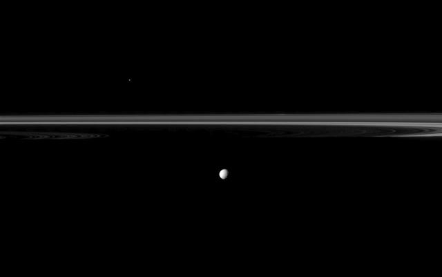 Saturn moon Mimas joins the planet rings which appear truncated by the planet shadow in this image from NASA Cassini spacecraft.