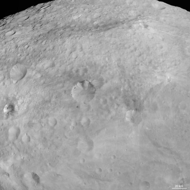 NASA Dawn spacecraft obtained this image of dark patches and stripes on crater walls on asteroid Vesta with its framing camera on August 18, 2011. The image has a resolution of about 260 meters per pixel.