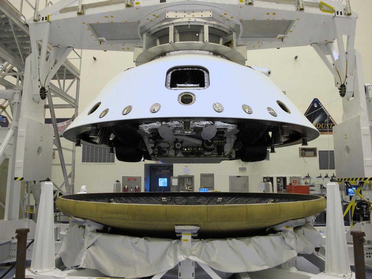 At the Payload Hazardous Servicing Facility at NASA Kennedy Space Center in Florida, the back shell powered descent vehicle configuration, containing NASA Mars Science Laboratory rover, Curiosity, is being placed on the spacecraft heat shield.