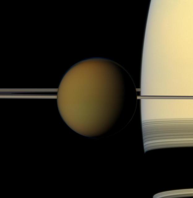 The colorful globe of Saturn largest moon, Titan, passes in front of the planet and its rings in this true color snapshot from NASA Cassini spacecraft.