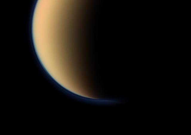 This view from NASA Cassini spacecraft look toward the south polar region of Saturn largest moon, Titan, and show a depression within the moon orange and blue haze layers near the south pole.