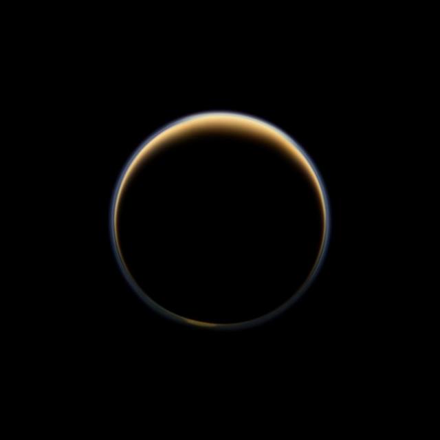 NASA Cassini spacecraft looks toward the night side of Saturn largest moon and sees sunlight scattering through the periphery of Titan atmosphere and forming a ring of color.