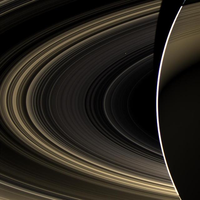 Peering over the shoulder of giant Saturn, through its rings, and across interplanetary space, NASA Cassini spacecraft spies the bright, cloudy terrestrial planet, Venus.