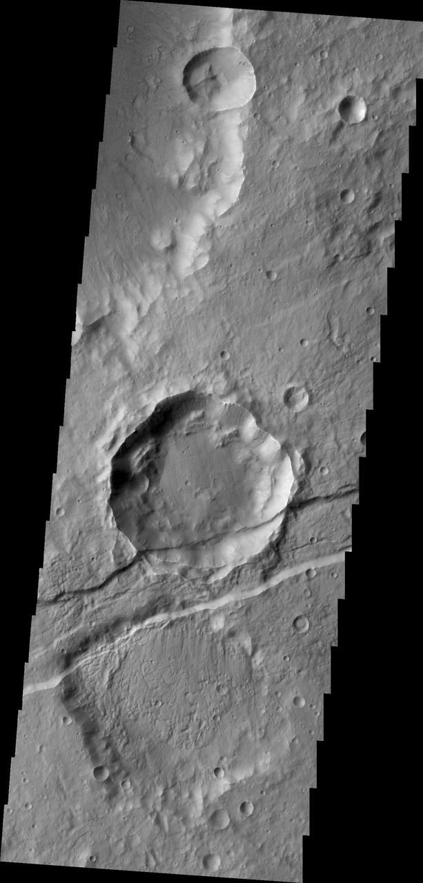 The downdropped block of surface seen in this image captured by NASA 2001 Mars Odyssey spacecraft is called a graben. The graben is younger than the crater, since the crater is cut by the graben.