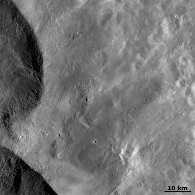This image from NASA Dawn spacecraft shows ejecta from two of the large Snowman craters on the left of the image. This ejecta smooths out asteroid Vesta surface in the rest of the image.