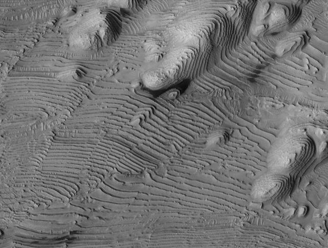 Rhythmic patterns of sedimentary layering in Danielson Crater on Mars result from periodic changes in climate related to changes in tilt of the planet in this image was taken by NASA Mars Reconnaissance Orbiter.