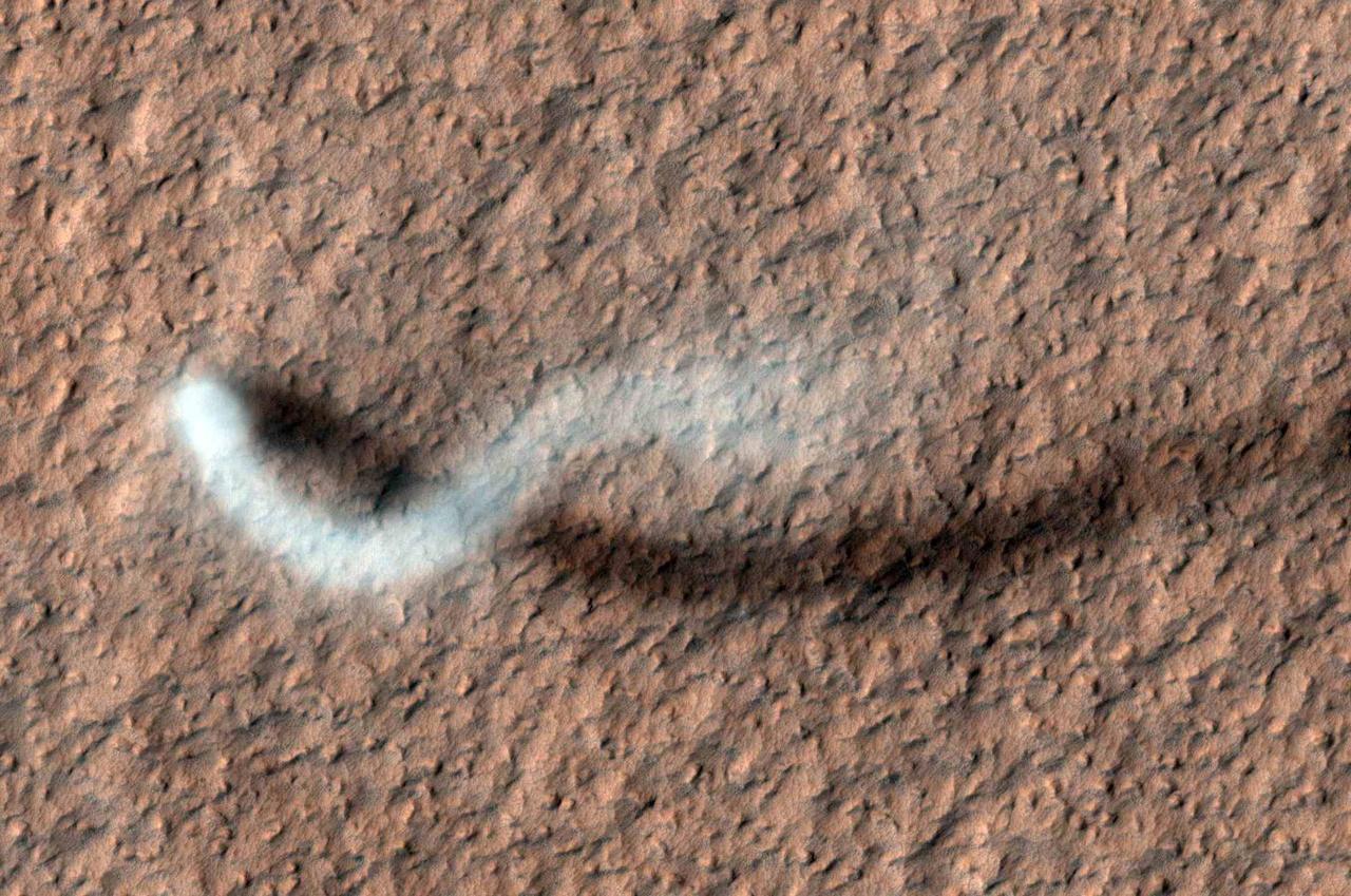 A towering dust devil casts a serpentine shadow over the Martian surface in this image from NASA Mars Reconnaissance Orbiter. The scene is a late-spring afternoon in the Amazonis Planitia region of northern Mars.