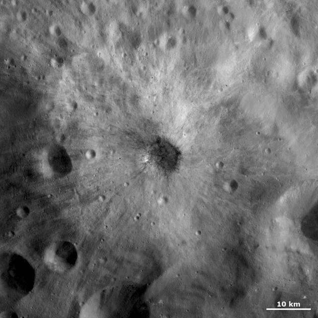 This image from NASA Dawn spacecraft is centered on a small, young, fresh crater with bright and dark ejecta rays extending from it. The crater is located in Vesta Tuccia quadrangle on asteroid Vesta.