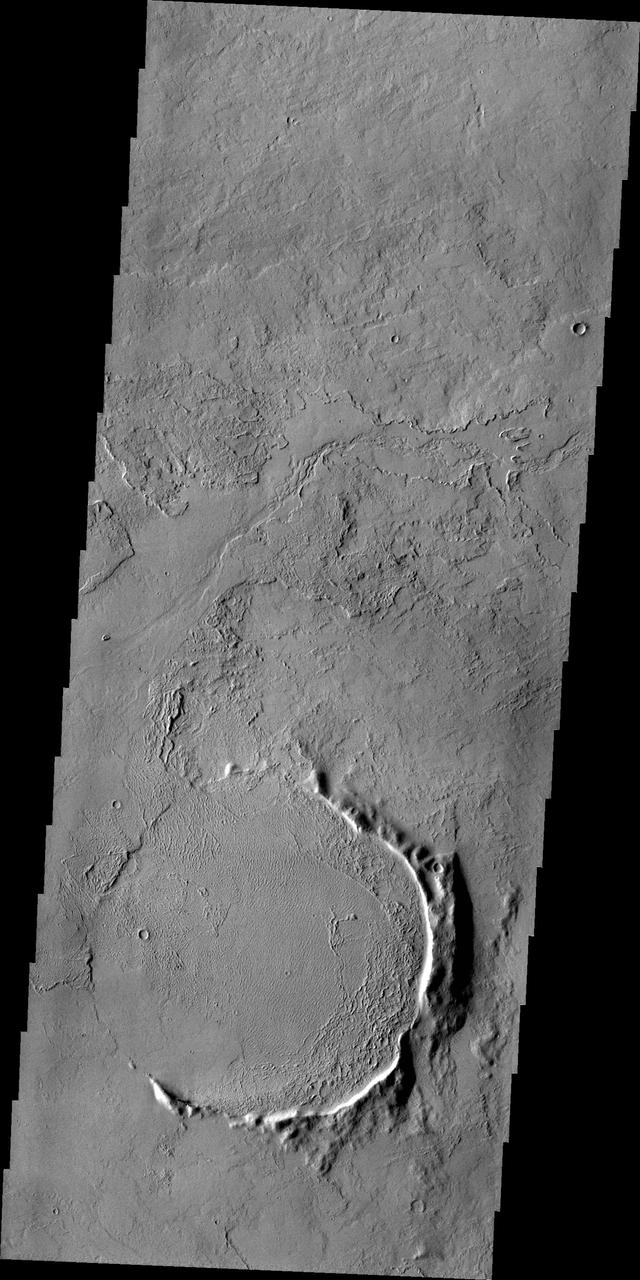 Only part of the rim of an unnamed crater remains visible above the lava flows in this region of Tharsis. This image is from NASA 2001 Mars Odyssey spacecraft.