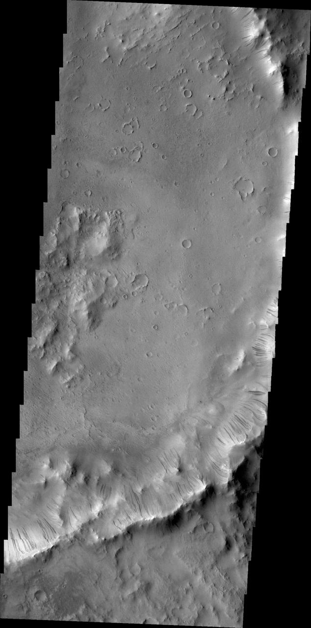 Dark slope streaks mark the rim of this unnamed crater withing Tikhonravov Crater in Terra Sabaea as seen by NASA 2001 Mars Odyssey spacecraft.