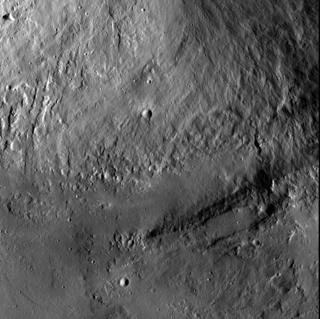 This image from NASA Dawn spacecraft shows an interior wall and southern terrace of Marcia crater on Vesta. Relatively smooth material covers much of the terrace and has flowed downslope toward the top of the image through channels.