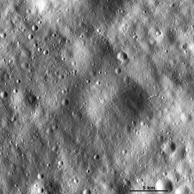 This image from NASA Dawn spacecraft shows many large subdued craters that have smaller, younger craters on top of them on asteroid Vesta. There are two large subdued craters in the center of the image, which have very degraded and rounded rims.